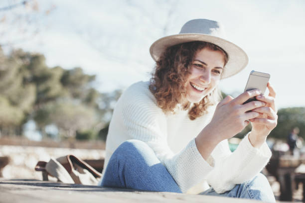 istock female traveler sitting at picnic table and using mobile phone 667296848
