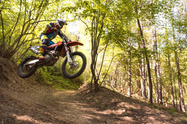 piloto de motocross pulando na extremo terreno no bosque. - x games - fotografias e filmes do acervo