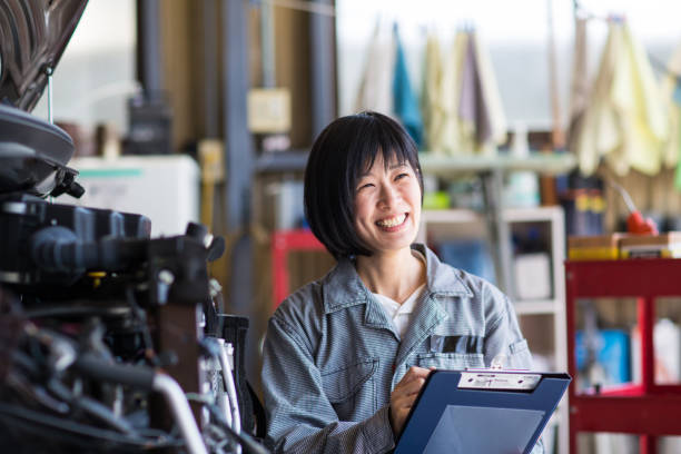 自動修理ガレージに破損した車を検査女性メカニック - mechanic ストックフォトと画像