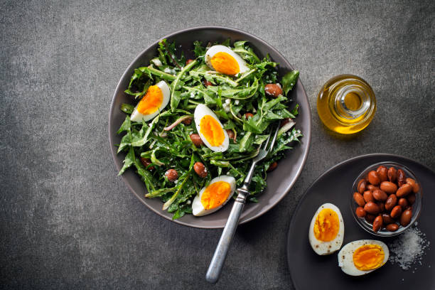 Dandelion salad Fresh dandelion salad with eggs and beans overhead shoot spring mix lettuce leaves stock pictures, royalty-free photos & images