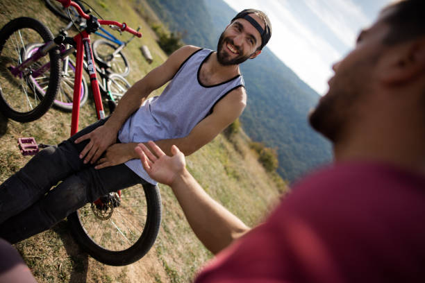 istock Happy man relaxing on mountain bike while talking with friend. 667308490
