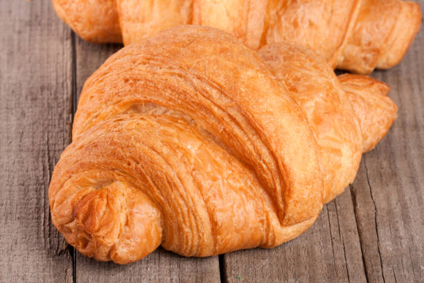 istock one croissant on old wooden board closeup 667308566