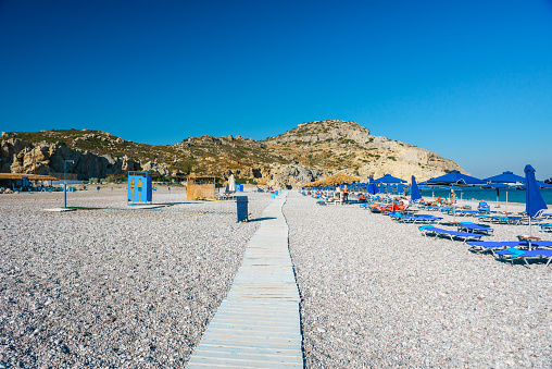 Pebbled Traganou beach with blue umbrellas, Rhodes Greece.
