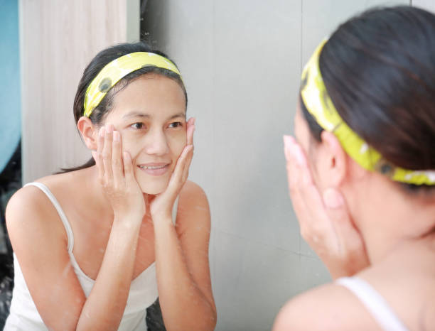 istock Woman cleaning washing her face reflect with bathroom mirror. 667319024