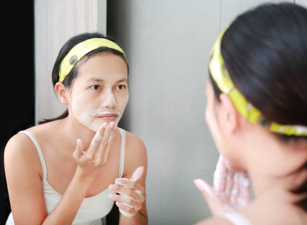 istock Woman applying foam cream to face reflect with bathroom mirror. 667319630