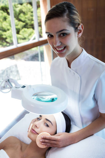 istock Masseuse cleaning woman face with cotton swabs 667320438