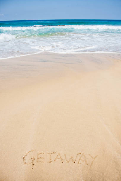 istock Getaway written in sand on clear beach 667325156