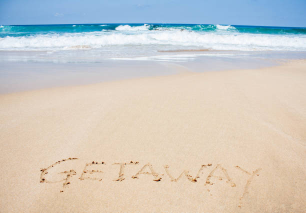 istock Getaway written in sand on clear beach 667328356