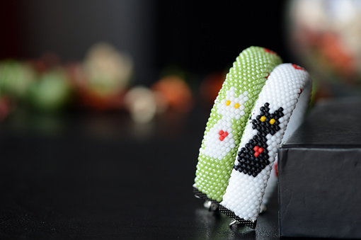 A pair of beaded bracelets with a black and white cat and hearts