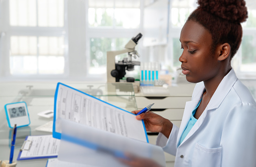 African-american biologist checks records in scientific lab or research facility. Focus on the face and eyelashes.