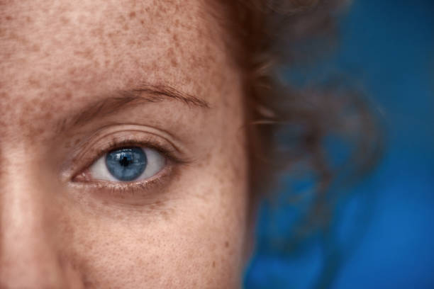 blue eye macro close up shot of woman with blue eye looking at camera, freckels on her skin, red hair. blue eyes stock pictures, royalty-free photos & images
