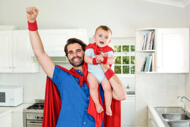 istock Father in superhero costume lifting son in kitchen 667332560