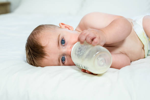 istock Baby boy drinking milk while lying on bed at home 667333210