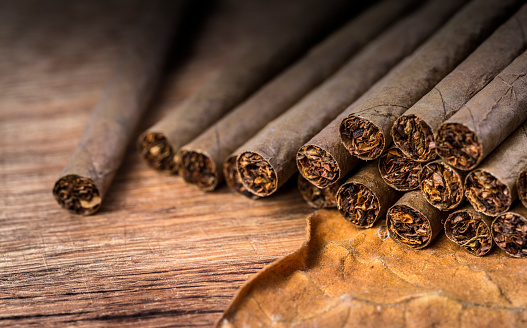 Cigarillo on wooden background close up with tobacco leaf selective focus