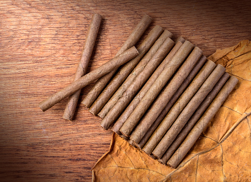 Cigarillo on wooden background close up with tobacco leaf