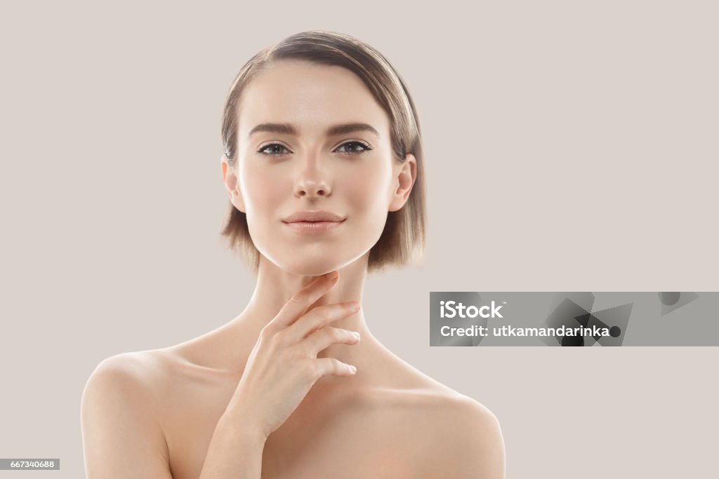 Beauty Woman face Portrait. Beautiful model Girl with Perfect Fresh Clean Skin. Beauty Woman face Portrait. Beautiful model Girl with Perfect Fresh Clean Skin. Blonde short hair Youth and Skin Care Concept. Isolated on a gray background Women Stock Photo