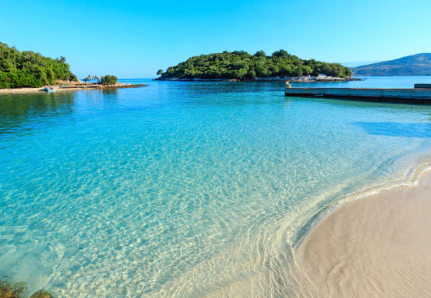 Ksamil beach, Albania. Beautiful Ionian Sea with clear turquoise water and morning summer coast view from beach (Ksamil, Albania). People unrecognizable. albania stock pictures, royalty-free photos & images