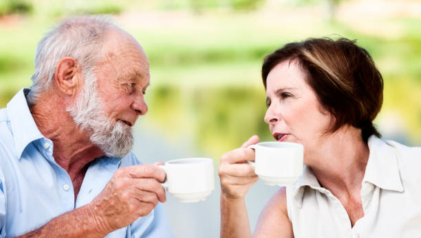 istock Elderly couple chat over coffee  by beautiful lake 667345010