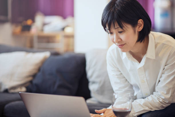 istock Mid adult woman using a laptop and sitting on sofa 667345648