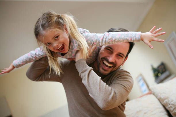 Cute young daughter on a piggy back ride with her dad. Looking at camera.