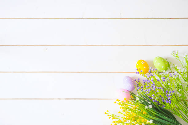 istock Spring flowers and easter eggs on white wooden table. View from above. 667349390