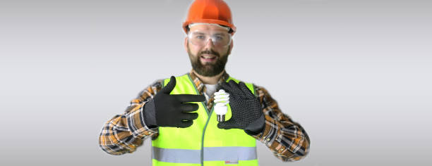 istock Worker in a helmet and protective clothing with a light bulb in 667352208