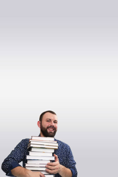 istock student adult beard man with stack of book in a library 667353078