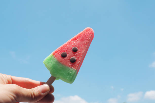 istock Hand holding a watermelon ice creams on blue sky background 667356742