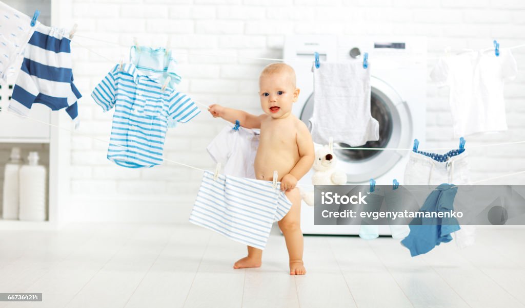 fun happy baby boy to wash clothes and laughs in laundry fun happy baby boy to wash clothes and laughs in the laundry room Baby - Human Age Stock Photo