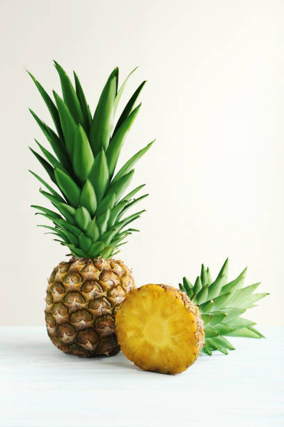istock Ripe pineapples on a white wooden background 667366558