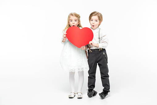 Excited little boy and girl holding big red paper heart