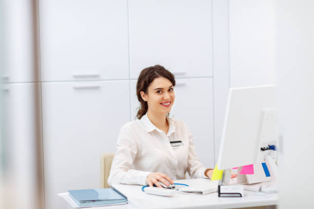 istock friendly young woman behind the reception desk administrator 667375080