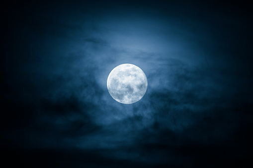 Full Moon and clouds on the night sky.