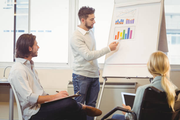 istock Smart businessman giving presentation as colleagues looking at it 667402782