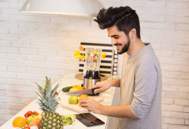 młody człowiek cięcia owoców w kuchni - fruit salad fruit healthy eating making zdjęcia i obrazy z banku zdjęć