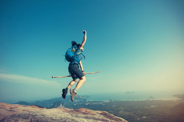 istock jumping on rocky mountain peak, freedom, risk, challenge, success concept 667403120