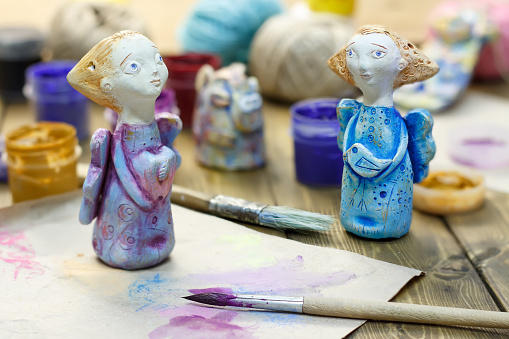 Paintbrush, paint in jars and handmade figurines \