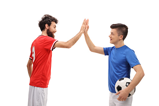 Father and son dressed in sport jerseys high fiving each other isolated on white background
