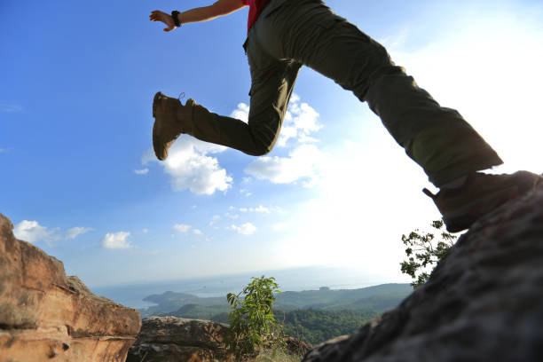 istock jumping over precipice between two rocky mountains at sunset 667410252