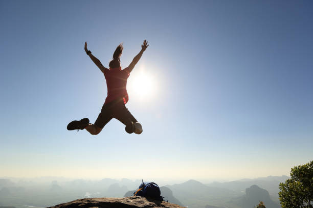 istock freedom woman backpacker jumping on sunrise mountain top 667419124