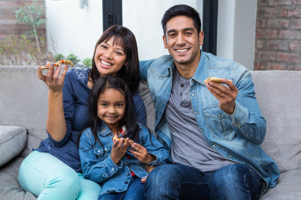 istock Smiling family eating pizza on the sofa 667419454