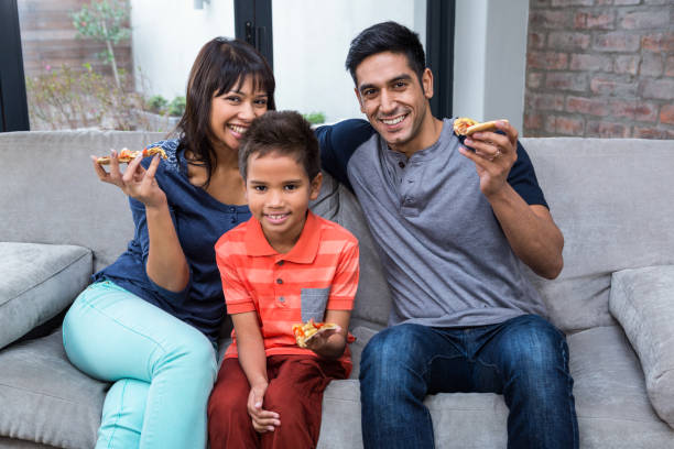 istock Smiling family eating pizza on the sofa 667421606