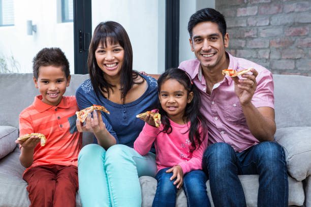 Happy family eating pizza on the sofa