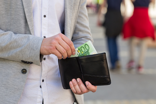 man hand take out one hundred euro banknote from his wallet on street