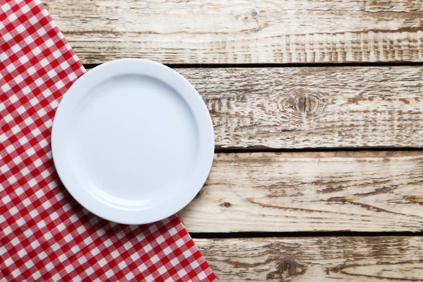 istock Empty plate with napkin on brown wooden table 667425226
