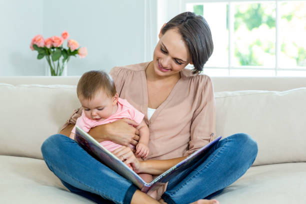 istock Mother showing picture book to son on sofa 667425230