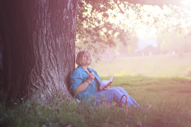 istock female in the park on sunset with book 667425876