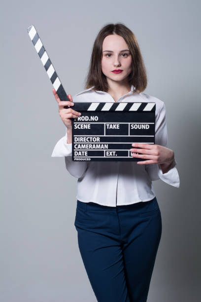 istock Young brunette in a white blouse with movie cracker 667427066