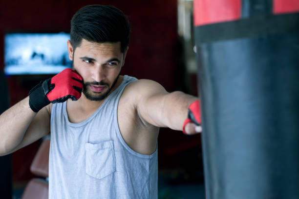 istock Boxer striking the punching bag at gym 667432202