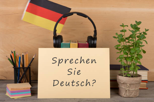 paper with text "sprechen sie deutsch?", flag of the Germany Learning languages concept - paper with text "sprechen sie deutsch?", flag of the Germany, books, headphones, pencils on wooden background german language photos stock pictures, royalty-free photos & images